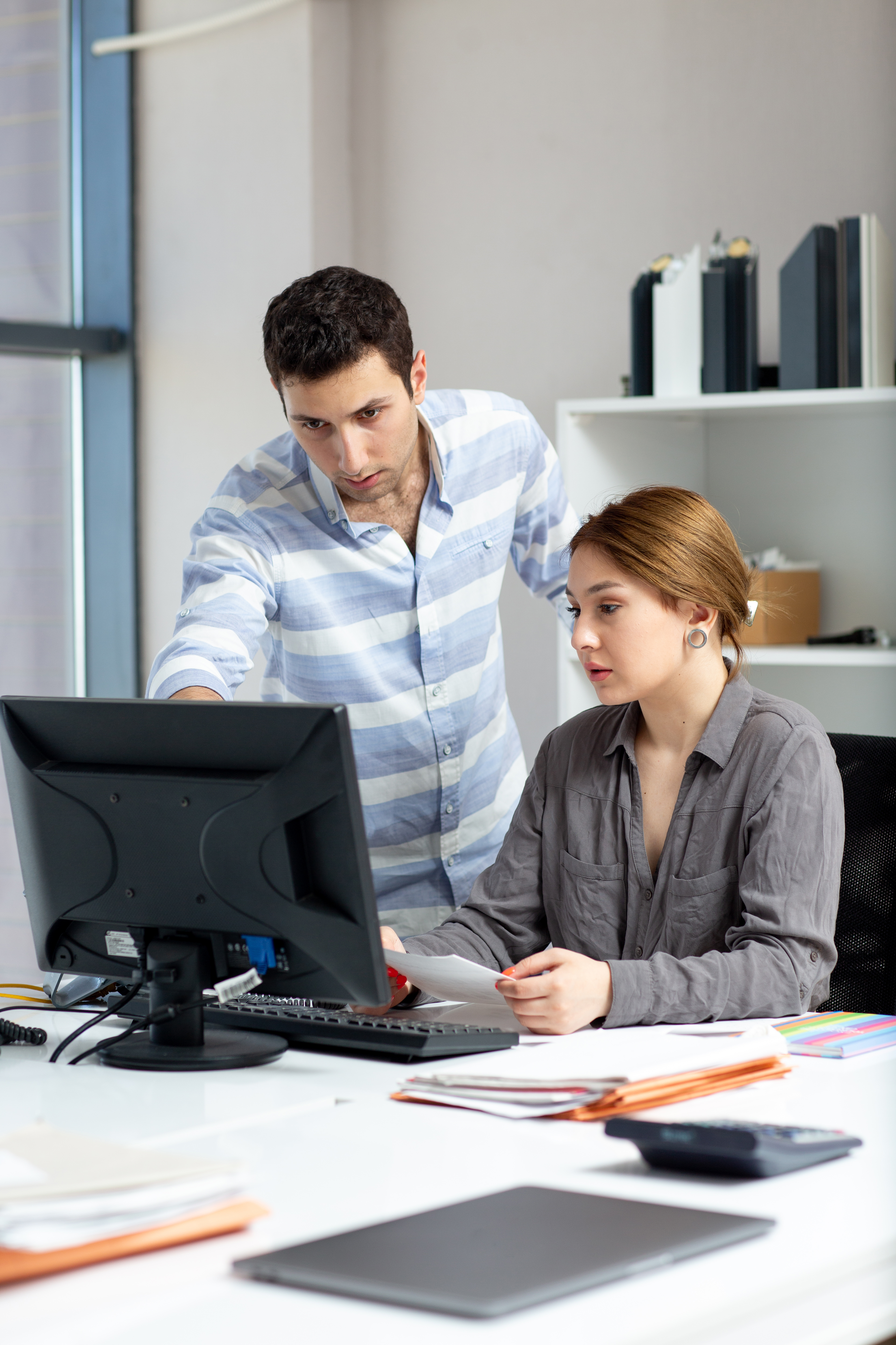 front-distanced-view-young-beautiful-lady-grey-shirt-talking-discussing-something-with-young-man-inside-office-daytime-building-job-activity